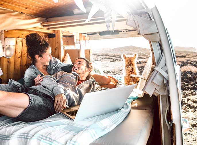 A man and woman lounging in a van during an outdoor camping trip